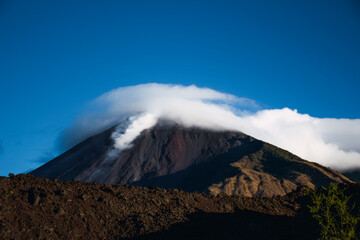 Volcán de Pacaya cubierto por una capa de nubes y expulsando material pirocástico en una ladera