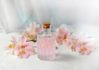 Obraz na płótnie Canvas Aromatherapy or spa composition with cosmetics oil glass and flowers on light background. Romantic perfume greeting concept for Womans day, Mothers day or wedding. Copyspace