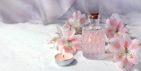 Obraz na płótnie Canvas Mock up spa aromatherapy concept with perfume glass or aroma oil glass, flowers and candle on light background. Massage. Wellness. Spring greeting card for Mothers day or wedding.