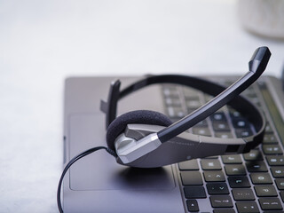 Headphones, headset, computer keyboard. Gray tones White background. Bright lighting. Close-up. Side view. There is an empty space for your insert. There are no people in the photo.