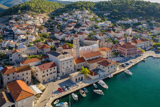 Red roofs and white stone houses in deep bay in village Pucisca on island Brac in Croatia. Aerial panoramic drone picture in august 2020