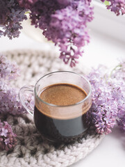 Fototapeta na wymiar A cup of coffee in blooming lilac flowers