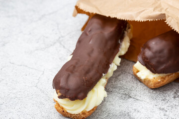 Chocolate eclair with a custard cream filling in a brown paper bag. Environmentally friendly...