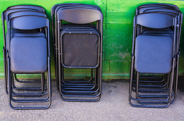 Black seats that fold. Folded  chairs on a green background