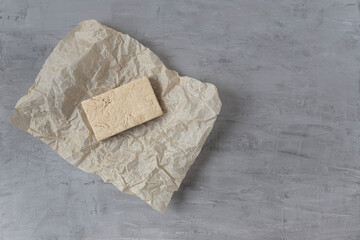 Peanut halva lying on parchment paper on a gray background. Top view, copy space. Traditional national dessert. Turkish, Arabic, Oriental cuisine.	