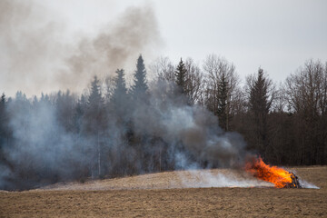 a fire caused by a person because of a campfire. a growing flame in a field on dry grass. a natural disaster. firefighters are working to extinguish the fire in smoke and smog