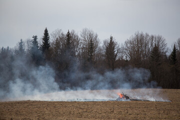 a fire caused by a person because of a campfire. a growing flame in a field on dry grass. a natural disaster. firefighters are working to extinguish the fire in smoke and smog