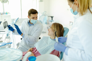 Photo of male dentist showing at patient's X-ray image in dental office.