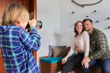 Happy family at home, little son with camera taking photo of hugging parents