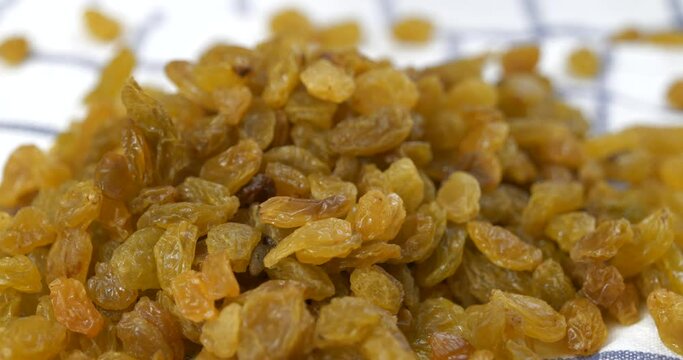 Fresh golden raisins falling onto a kitchen towel in slow motion
