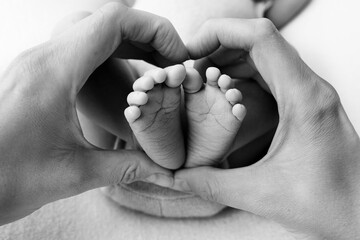 Feet of a newborn in the hands of a father, parent. Studio photography, black and white. Happy family concept.