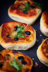 Selective focus. Mini pizzas on a black background. Appetizing mini pizzas.