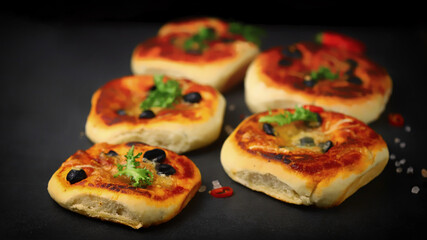 Selective focus. Mini pizzas on a black background. Appetizing mini pizzas.