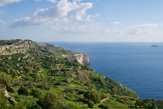 DINGLI CLIFFS, MALTA - JAN 02nd, 2020: Sea coast of Malta with Dingli Cliffs and Fifla Island in the background. Scenic high rising cliffs with panoramic view