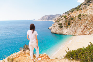 Young woman traveler looking on picturesque sea bay with beautiful Kaputas beach with turquoise water. Summer beach holiday in Turkey resort