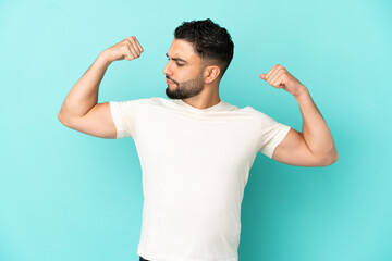 Young arab man isolated on blue background doing strong gesture