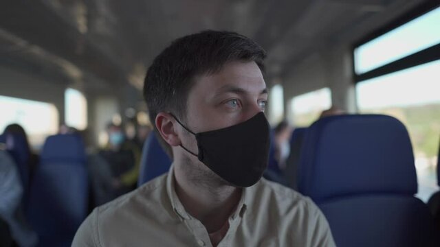 Male passenger wearing face mask during covid-19 lockdown inside train. New normal lifestyle concept. Social distancing when traveling by public transport. Commuting during coronavirus pandemic