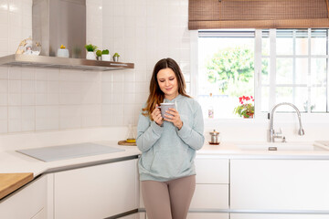 Spanish young girl taking tea in her kitchen.