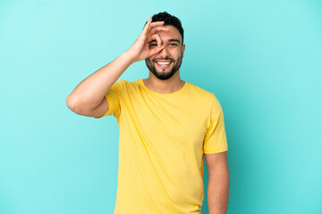 Young arab man isolated on blue background showing ok sign with fingers