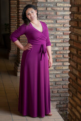 Hispanic latina model in a purple pink dress smiling and posing in location for a fashion portrait photoshooting  as a Mexican woman beauty concept