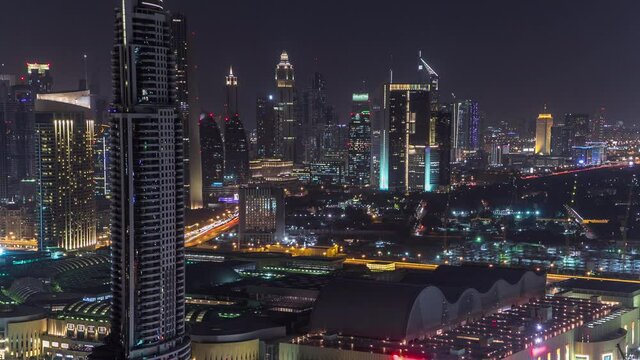 Dubai downtown skyline day to night transition aerial timelapse. Top view of Sheikh Zayed road with numerous illuminated towers and skyscrapers. Traffic on the road. Famous landmark
