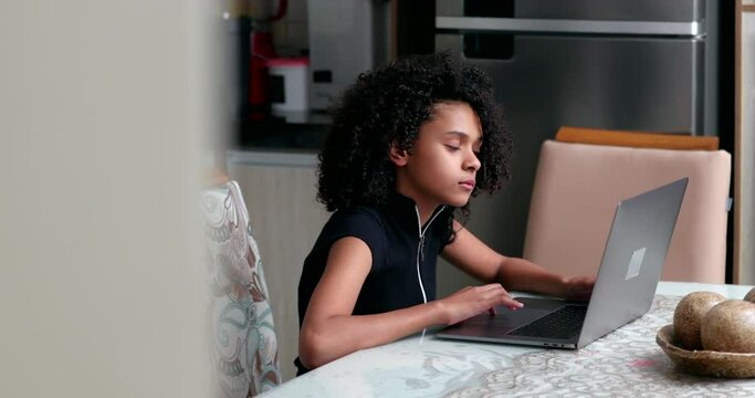 Preteen girl using laptop at home. Black child typing on computer