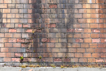 Unusual bricks with a grooved pattern in an old wall which is showing its age with pieces of the...