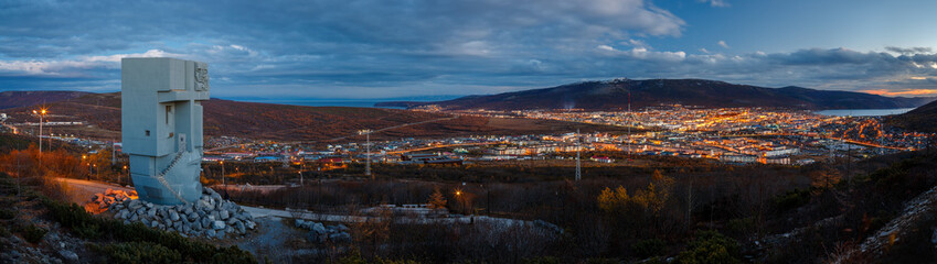 Evening panorama of the memorial complex Mask of Sorrow and the environs of the city of Magadan. View of the monument and the seaside town. Magadan, Magadan Region, Siberia, Russia.