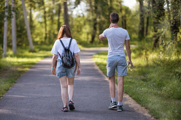 Obraz premium A young man and a woman walking in a park in summer.