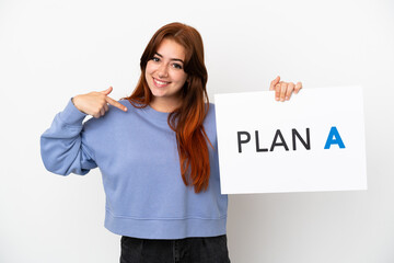 Young redhead woman isolated on white background holding a placard with the message PLAN A and  pointing it