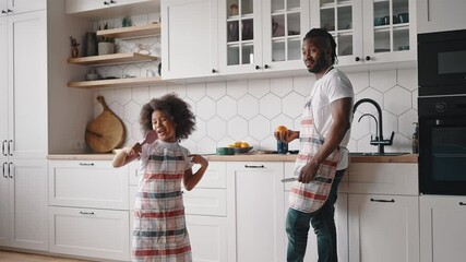 Little popstar. Cute curly african american girl in apron singing with cooking spatula pretending to be popular singer