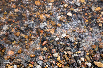 the water washes the multi-colored pebbles on the shore. flat lay.
