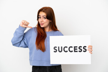 Young redhead woman isolated on white background holding a placard with text SUCCESS with proud gesture