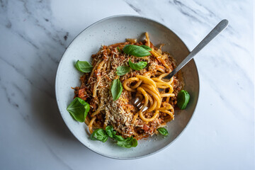 Vegan lentil pasta, bucatini with home made tomato lentil sauce and basil on white concrete background