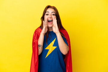 Super Hero redhead woman isolated on yellow background shouting and announcing something