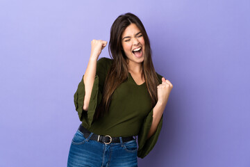Teenager Brazilian girl over isolated purple background celebrating a victory