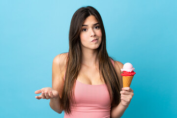 Teenager Brazilian girl holding a cornet ice cream over isolated blue background making doubts...