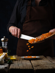 Cooking a vegetable pie. The photo shows the process of slicing carrots for the filling. On the left in the photo are the ingredients for making a vegetable pie. In the photo, levitation.