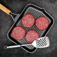 Raw Steak Burgers Cutlets On Grill Pan. Burgers Patties from Marbled Beef Meat in Frying Pan on Black Background, Overhead View. Griddle Pap and Ground Beef Meat Patties for Grilling, Top View.