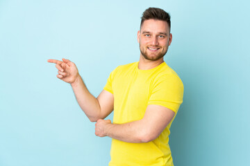 Russian handsome man isolated on blue background pointing finger to the side