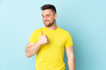 Russian handsome man isolated on blue background giving a thumbs up gesture