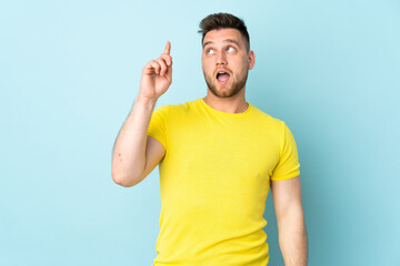 Russian handsome man isolated on blue background intending to realizes the solution while lifting a finger up