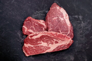 Raw Steaks. Sirloin Beef Steaks, Overhead View. Many Raw Striploin Steaks from Marbled Beef on Black Background. Group of Black Angus Beefsteaks. Raw Sirloin Cuts. Uncooked Prime Beef Steaks.