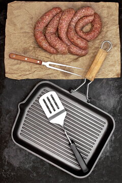 Raw Stuffed Sausages, Empty Grill Pan and Grill Tools On Rustic Black Table Background, Top View. Raw Sausages In Natural Casing. Sausages For Grilling or Frying On Paper Overhead View.