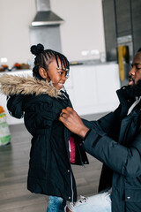 Father helps daughter with braids to put on her coat