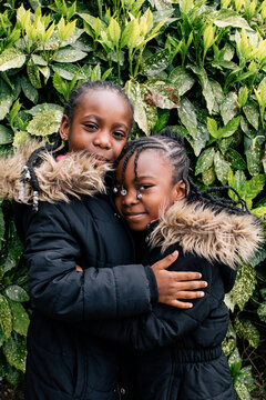 Two little girls with braids hugging one another