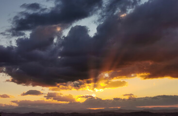 Fototapeta na wymiar Raggi di sole trafiggono le nuvole al tramonto