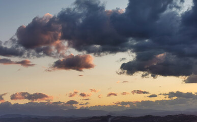 Fototapeta na wymiar Nuvole colorate sopra le montagne al tramonto