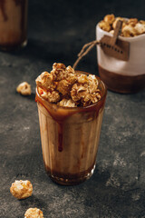 Caramel milkshake with popcorn on dark background. Selective focus.