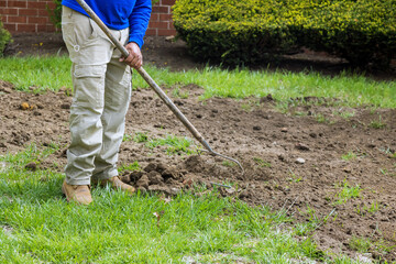 Municipal services worker gardener with a metal rake at the end active work
